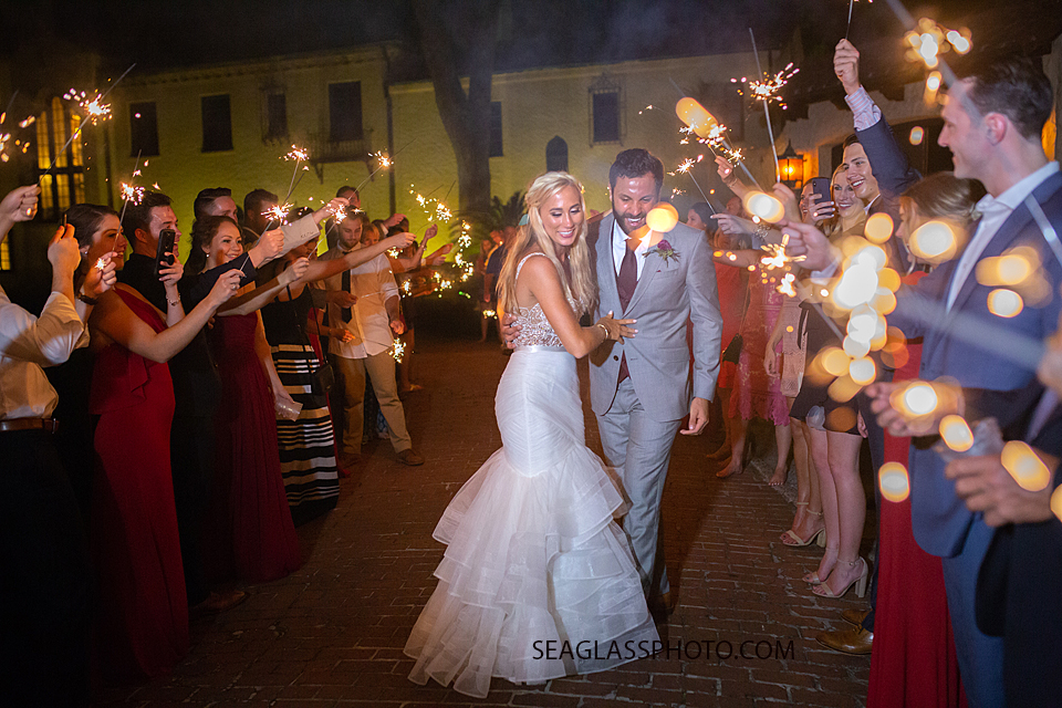 Bride and Groom walk under a path of sparklers held by the guests photographed by a Vero Beach Photographer