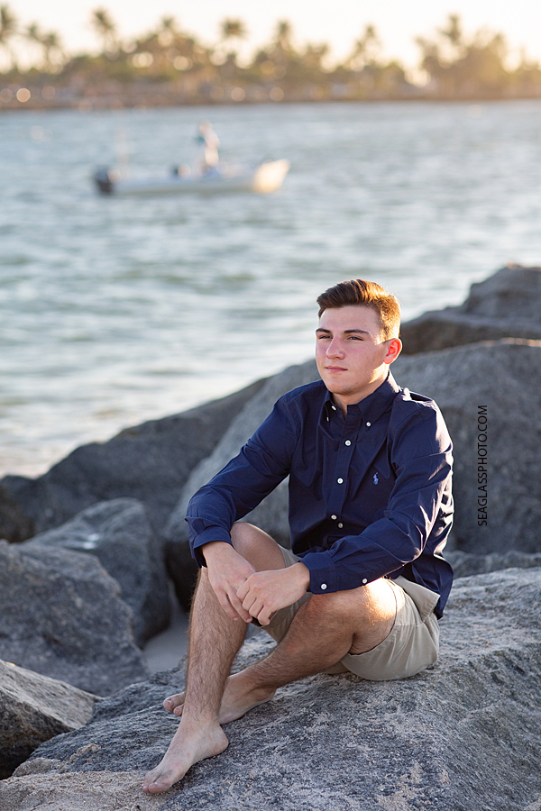 Young man sits by the bay during his senior pictures in Vero Beach Florida
