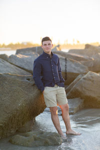 Young man stands on the beach during his senior pictures in Vero Beach Florida