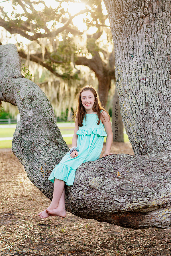 Young girl sits on a tree branch in Riverside Park in Vero Beach Florida