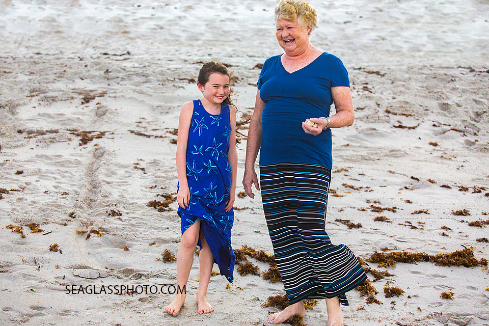 Grandma and grand-daughter stay close together and away from the ocean collecting shells during family photos in Vero Beach Florida