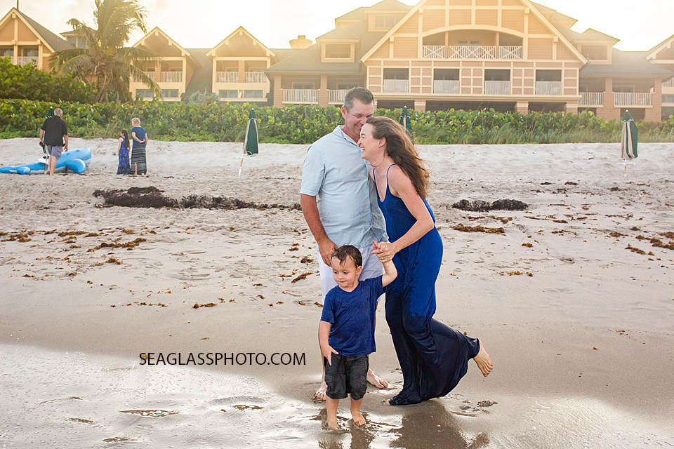 Mother, Father and Son laugh and watch the waves during family photos in Vero Beach Florida
