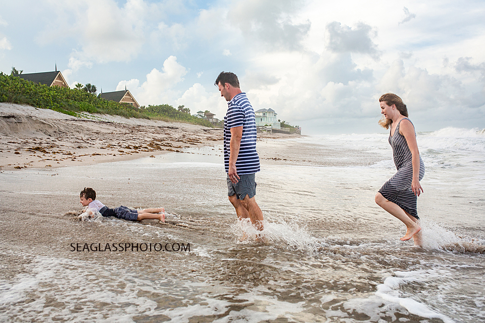 Mother and father watch their son tumble in the water during family photos in Vero Beach Florida
