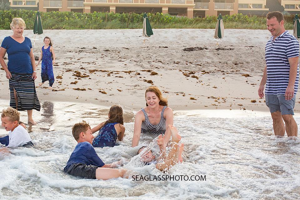 Mother goes to grab her son as they sit in the wake of the ocean during family photos in Vero Beach Florida