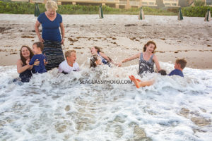 Family tumbles in the waves during family photos in Vero Beach Florida
