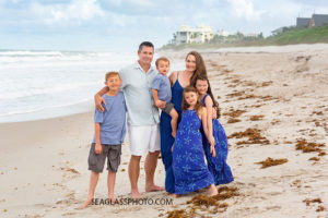 Family of six gather for a family photo on the beach during family photos in Vero Beach Florida
