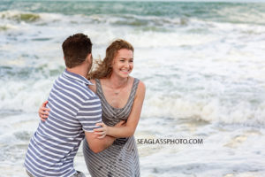Husband and wife mess around trying to not get pushed over by the waves during family photos in Vero Beach Florida
