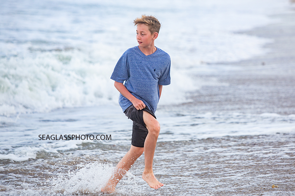 Young boy runs away from the waves of the ocean during family photos in Vero Beach Florida