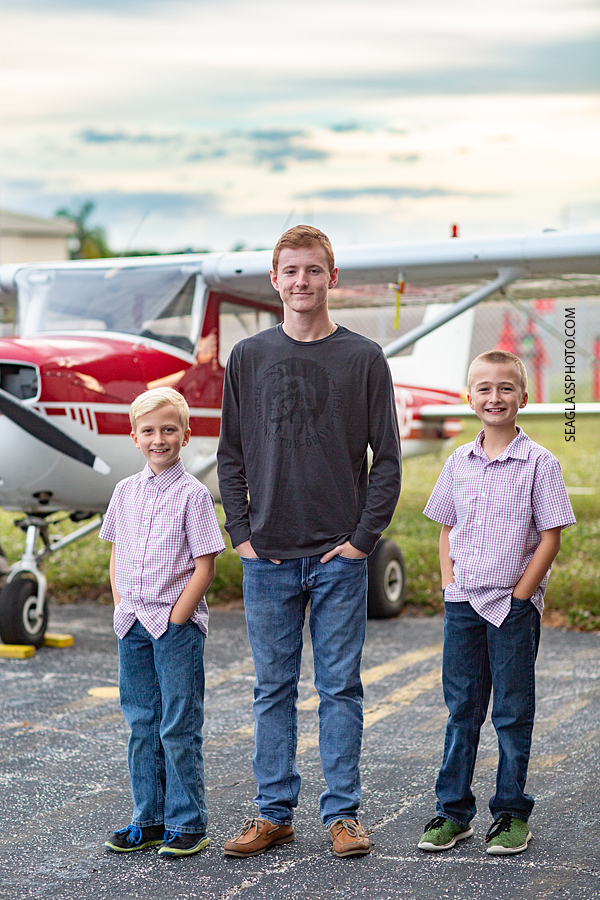 Three brothers pose for a picture in front of an airplane during family photos in Vero Beach Florida