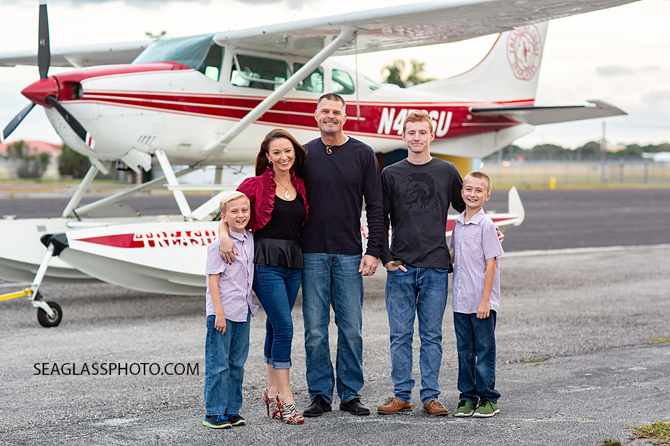 Family poses for a photo in front of an airplane during family photos in Vero Beach Florida
