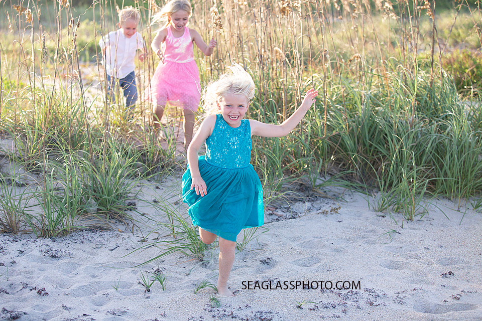 Siblings run out of the duns on the beach during family photos in Vero Beach Florida
