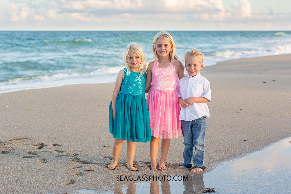 Siblings smile for the camera in front of the ocean during family photos in Vero Beach Florida
