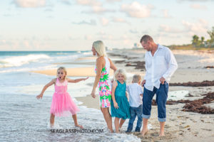 Family in bright colors look out onto the ocean during family photos in Vero Beach Florida