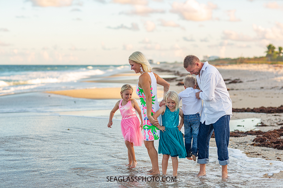 Family plays in the wake of the ocean during family photos in Vero Beach Florida