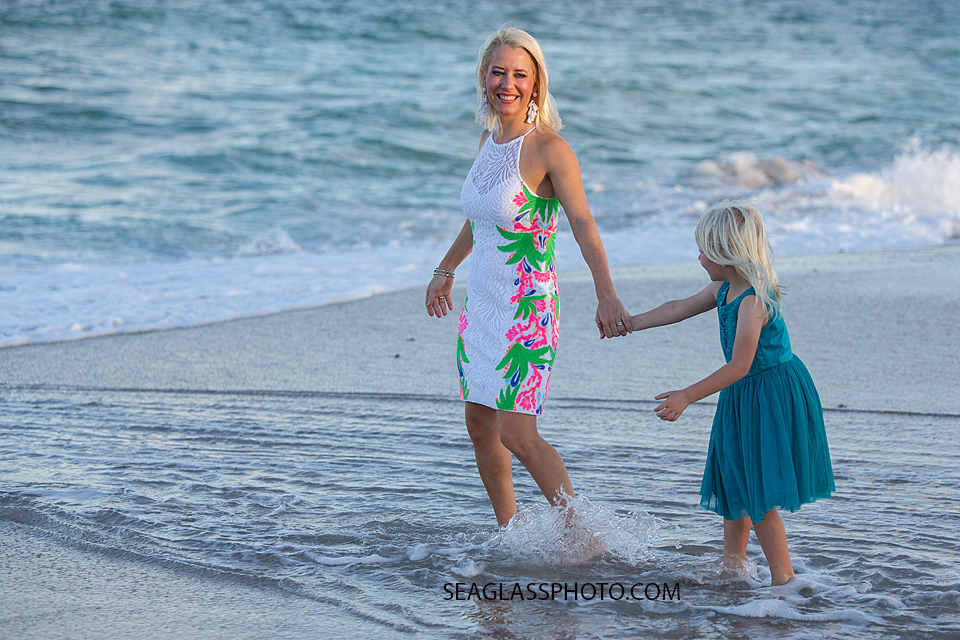 Mother and daughter walk in water of the ocean during family photos in Vero Beach Florida