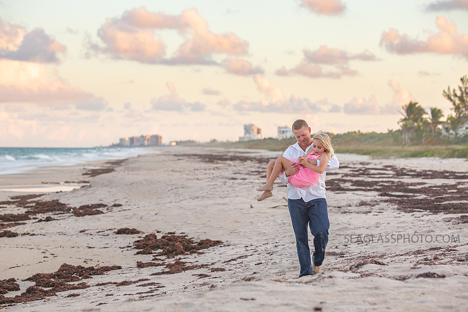 Father carries his daughter on the beach during family photos in Vero Beach Florida