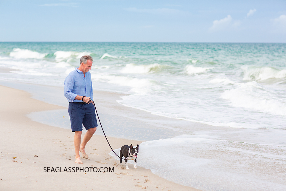 Father walks his dog on the beach during family photos in Vero Beach Florida