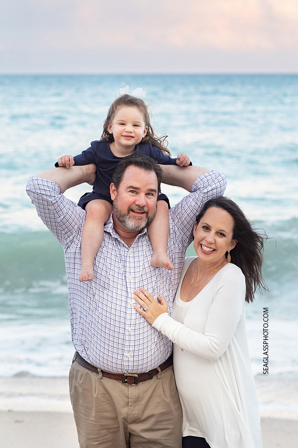 Dad holds his daughter on his shoulder with mom during family photos in Vero Beach Florida
