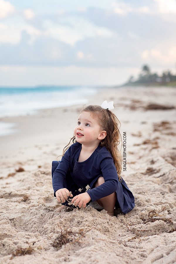 Young girl plays in the sand on the beach during family photos in Vero Beach Florida
