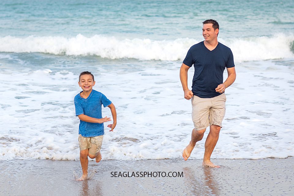 Father and Son run away from the waves on the beach during their family photoshoot in Vero Beach Florida