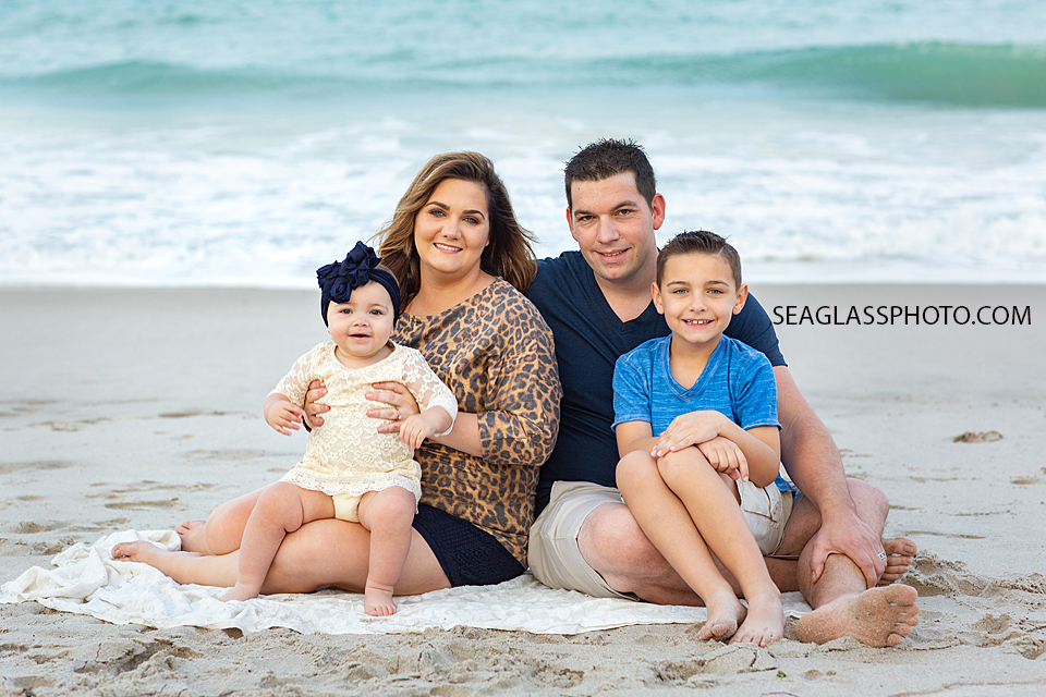 Family sits together on the beach during their family photoshoot in Vero Beach Florida