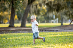Young boy runs in the grass during family photos at Riverside in Vero Beach Florida