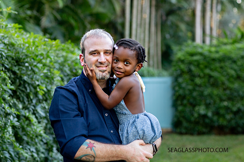 Little girl hugs her dad while he holds her during family photos in Vero Beach Florida