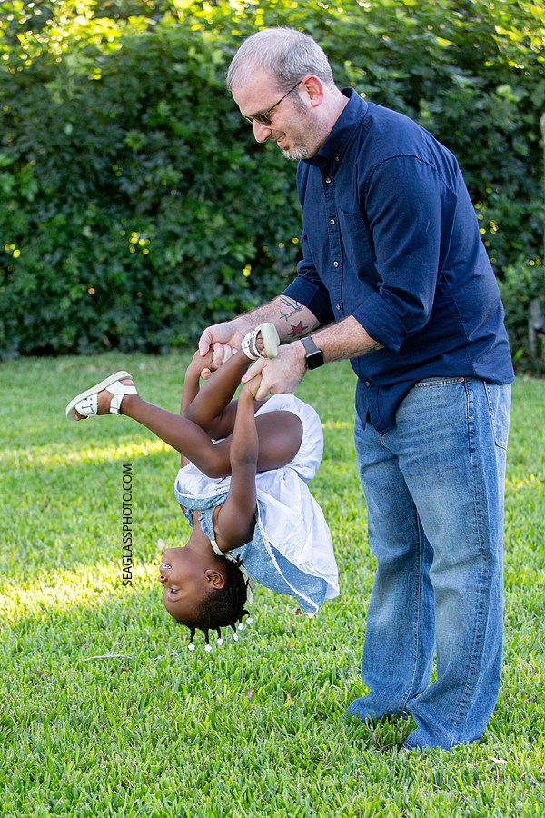 Little girl needs help from her dad to do a twirl in the air during family photos in Vero Beach Florida