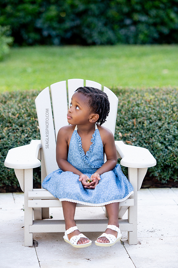 Little girl looks off in the distance as she sits in her chair during family photos in Vero Beach Florida
