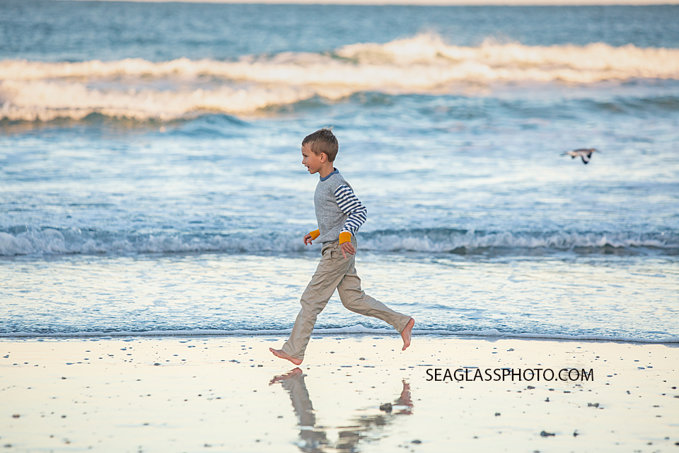 Young boy runs on the beach at the Fort Pierce Inlet during family photos