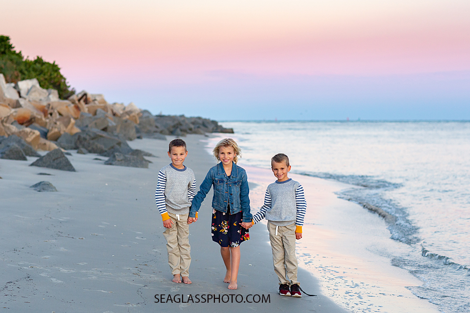 Siblings walking on the beach holding hands at the Fort Pierce Inlet during family photos