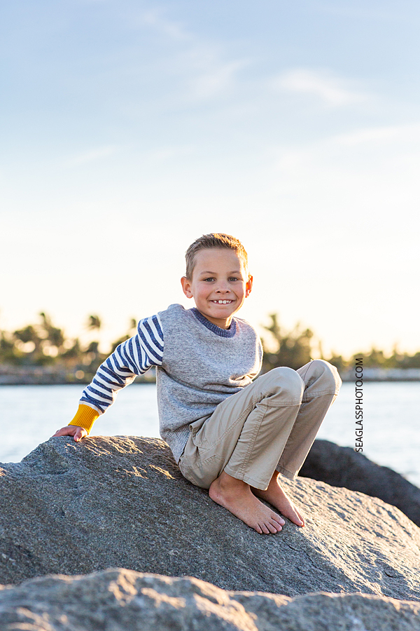 Young boy sits on top of a giant rock at the Fort Pierce Inlet during family photos