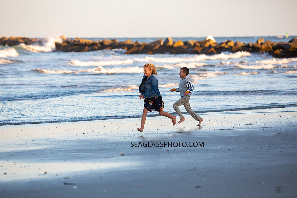 Young girl runs with her brother on the beach at the Fort Pierce Inlet during family photos