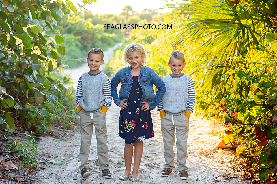 Siblings smile for the camera while standing in the sea grape bushes at the Fort Pierce Inlet during family photos