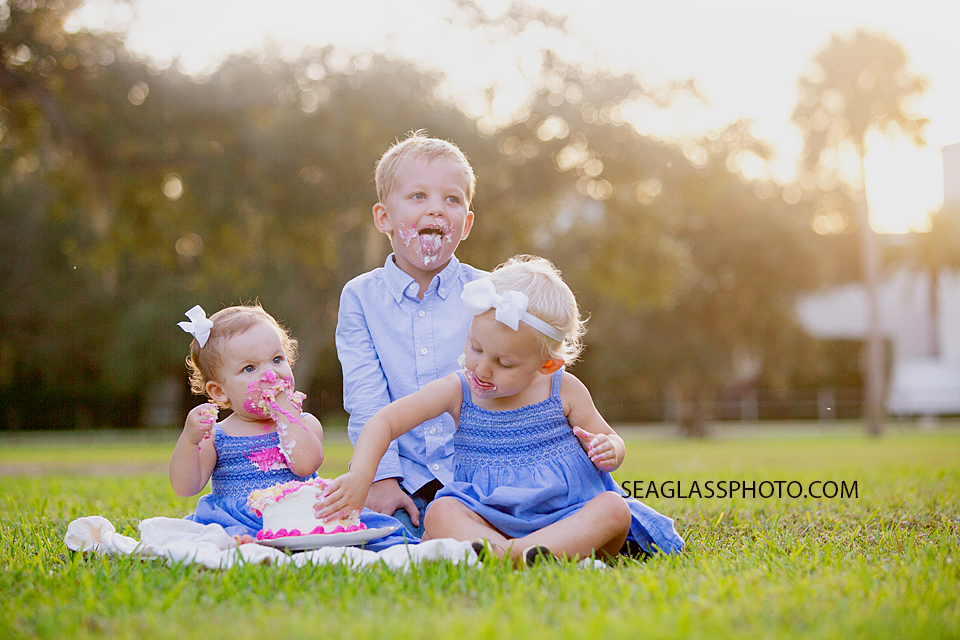 Siblings join in the fun to eat the cake during family photos at Riverside in Vero Beach Florida