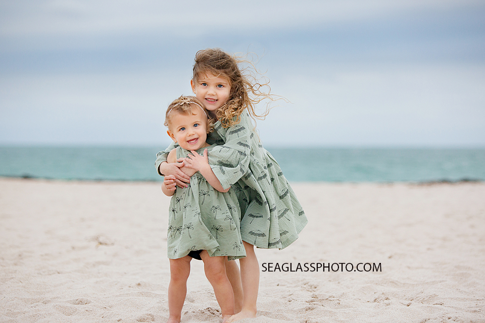 Sisters hug each other on the beach during family photos in Vero Beach Florida