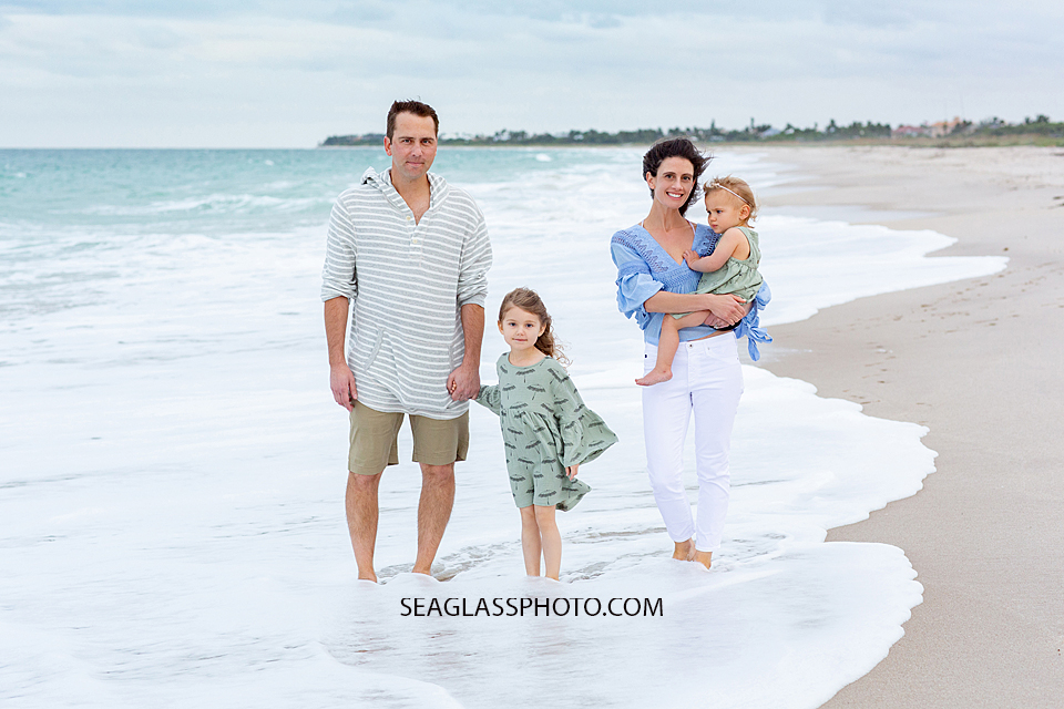 Family of four walks on the beach during family photos in Vero Beach Florida