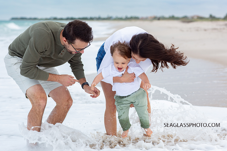 Close up of mom and dad playing with their son in the water during family photos in Vero Beach Florida