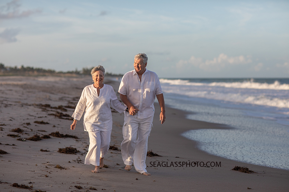 Husband and wife walk on the beach together during family photoshoot in Vero Beach Florida