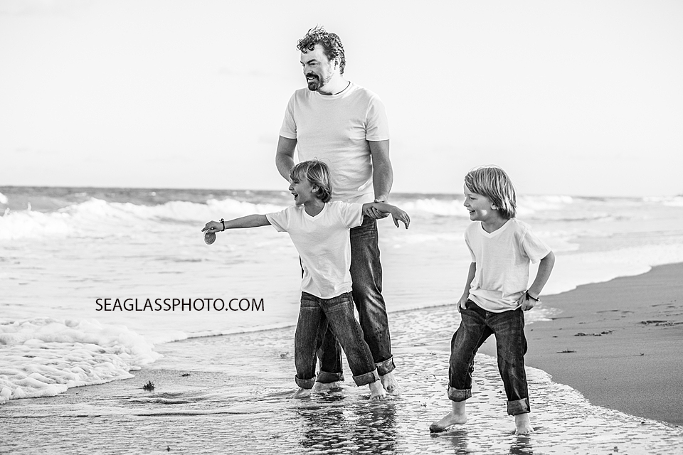 Black and white photo of a father and his sons looking out onto the ocean during family photoshoot in Vero Beach Florida