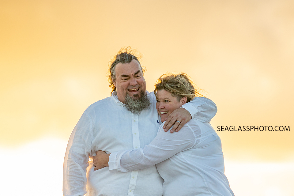 Husband and wife hugging with a beautiful back ground behind them during family photoshoot in Vero Beach Florida