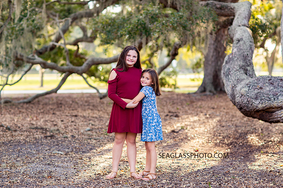 Sisters hug together under the trees during sister photoshoot in Vero Beach Florida