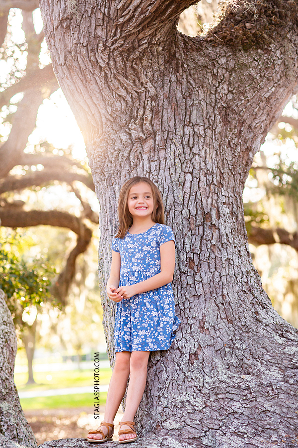 Young girl stands up in a tree during sister photoshoot in Vero Beach Florida