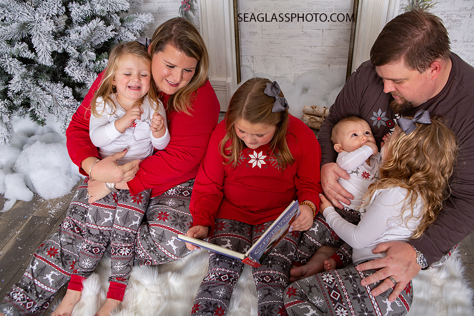 Young girl reads a Christmas story to her family during holiday family photos in Vero Beach Florida