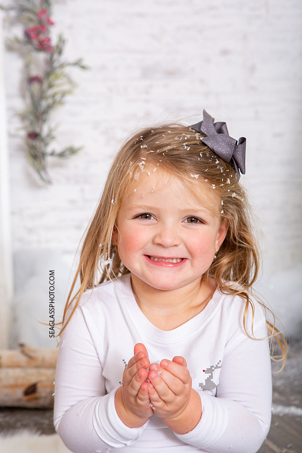 Little girl playing with snow during holiday family photos in Vero Beach Florida