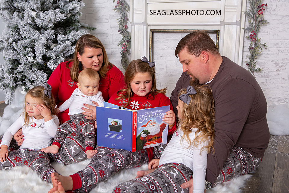 Family gathers around to read a Christmas book during holiday family photos in Vero Beach Florida