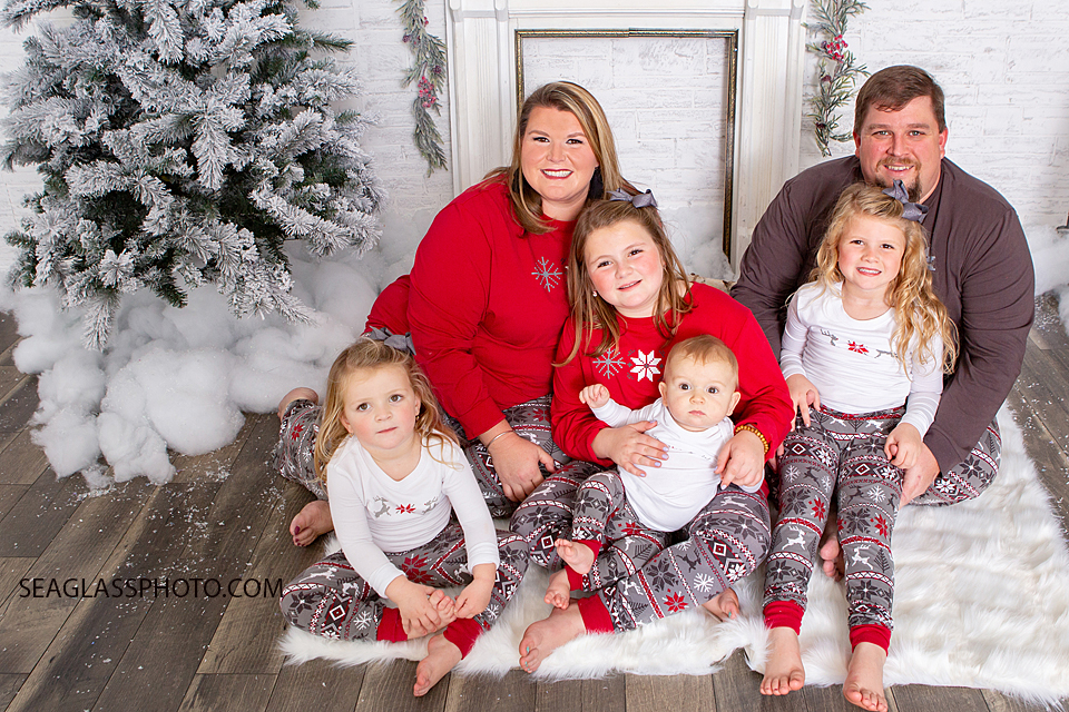 Family gathers by the Christmas tree wearing matching pajamas during holiday family photos in Vero Beach Florida