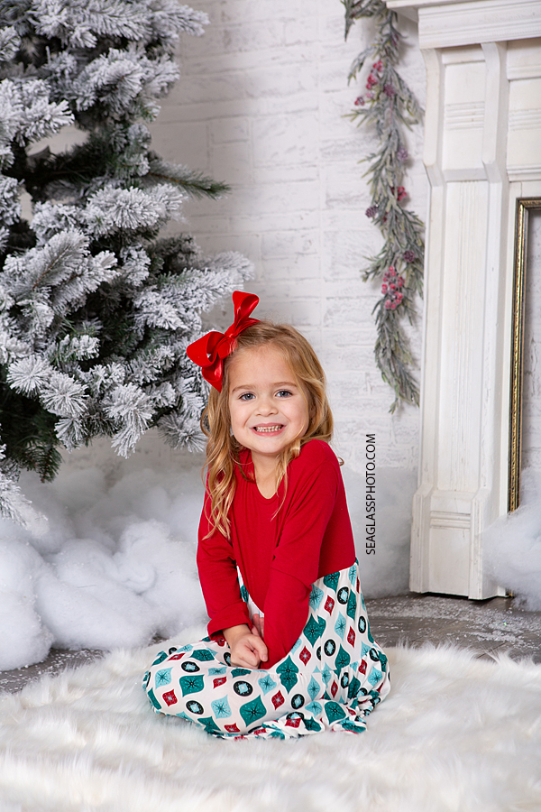 Young girl sits by the Christmas tree for Christmas photos in Vero Beach Florida