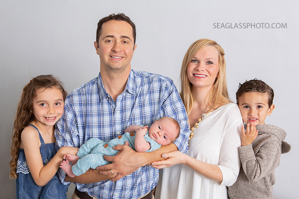 a stand up shot of the family holding their new little brother/son during newborn photoshoot in Vero beach Florida