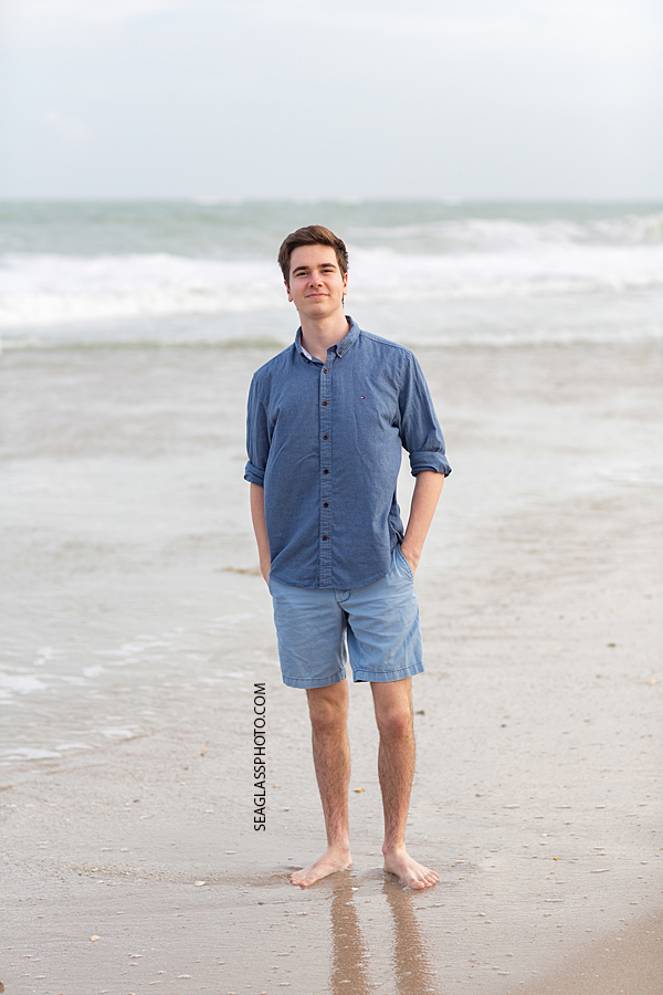 Young man stands by the beach during family photoshoot on the beach in Vero Beach Florida